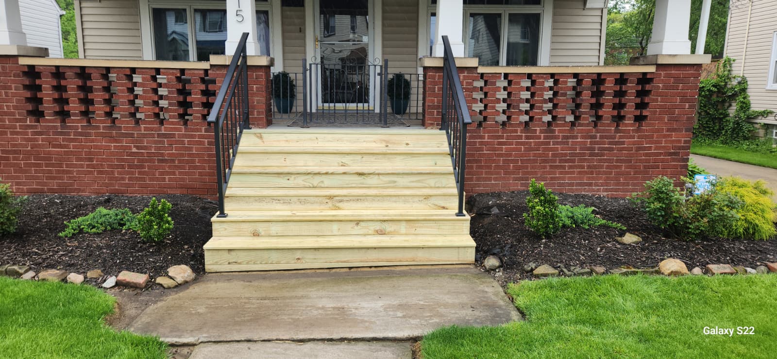 Front porch steps with new wood treads and black railings
